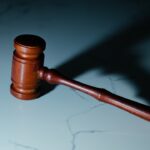 A wooden gavel resting on a marble surface, casting a shadow.