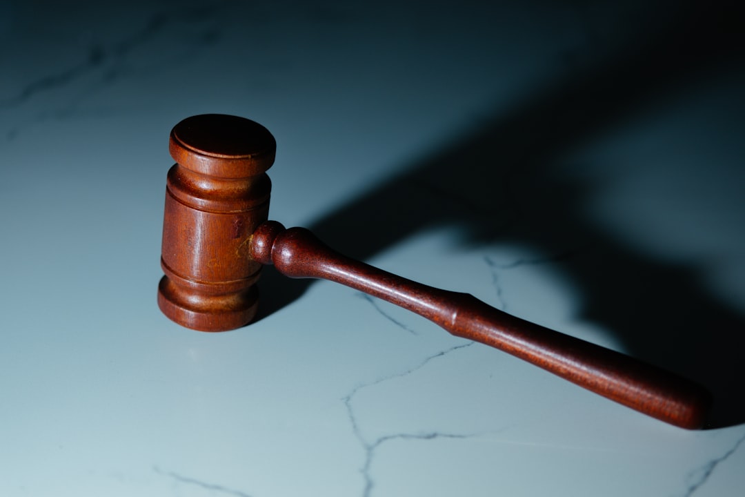 A wooden gavel resting on a marble surface, casting a shadow.